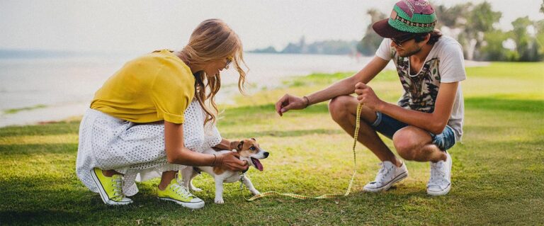dos personas jugando junto a un cachorro